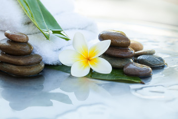 Fototapeta na wymiar Stones, leaves, flower and white towel for body massage