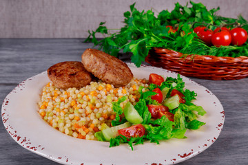 Pork cutlets, couscous with vegetables and arugula.