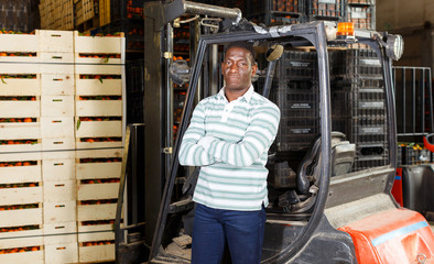 Fototapeta na wymiar African American man standing near forklift at fruit warehouse