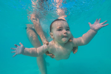 Obraz na płótnie Canvas Little baby boy swimming underwater in blue tropical sea