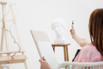 Young woman artist draws a pencil on canvas.