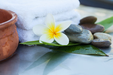 Obraz na płótnie Canvas spa flower and stones and white towel for massage treatment on white background.