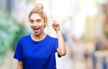 Young beautiful blonde and blue eyes woman wearing blue t-shirt over isolated background pointing finger up with successful idea. Exited and happy. Number one.