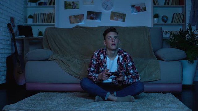 Student playing video games late at night instead studying, game addicted boy