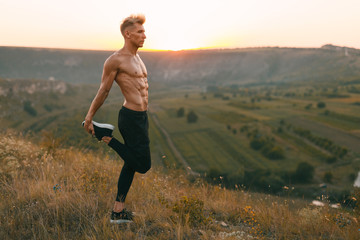 Fototapeta premium Handsome athlete warming up in countryside