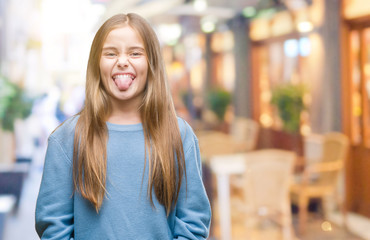 Young beautiful girl wearing winter sweater over isolated background sticking tongue out happy with funny expression. Emotion concept.