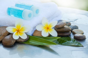 Fototapeta na wymiar Tropical flower with towel, bottles for spa and stones