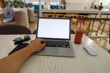 laptop in cafe table with white screen and fruit smoothie near it