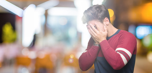 Young handsome man over isolated background with sad expression covering face with hands while...