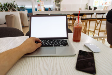 laptop in cafe table with white screen and fruit smoothie near it
