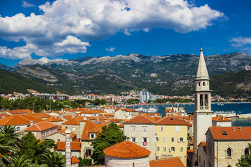Fototapeta premium View of the old town of Budva in Montenegro. Summer day and clouds over the mountains in the background. Soft focus and blur.