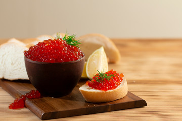 red caviar in a ceramic dish on a wooden background in a rustic style with space for text