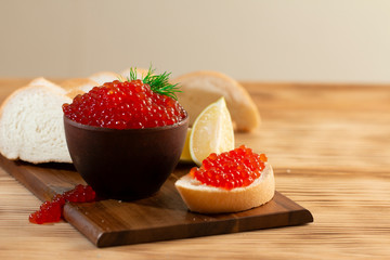 red caviar in a ceramic dish on a wooden background in a rustic style with space for text
