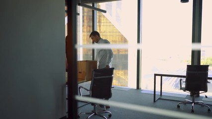 Man in office bring his box and belongings. He and his colleagues move into new modern office in business district. 4k UltraHD.