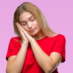 Young caucasian woman over isolated background sleeping tired dreaming and posing with hands together while smiling with closed eyes.