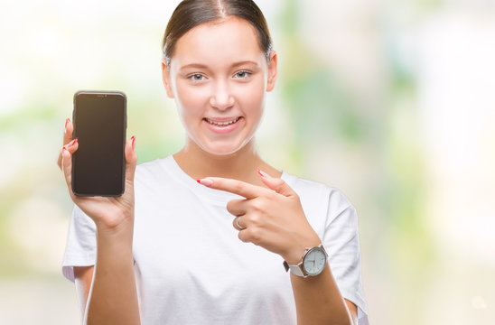Young beautiful caucasian woman showing smartphone screen over isolated background very happy pointing with hand and finger