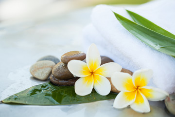 Fototapeta na wymiar Flowers and towel with stones for spa treatment