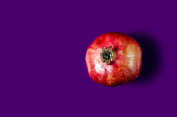 Pomegranate red fruit on purple background, top view