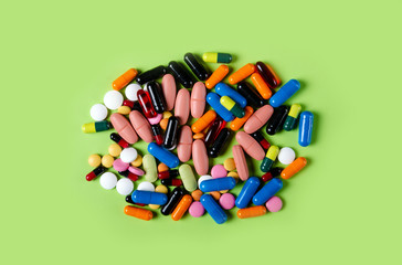 Colorful pills medical on green background top view, pharmacy concept