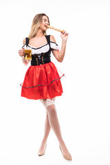 Young woman in a dirndl with a beer and a pretzel isolated on white background. Full height portrait.