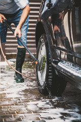 man washes modern car in  yard