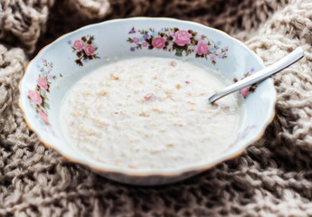 Sweet oatmeal with pieces of fruit in a porcelain bowl