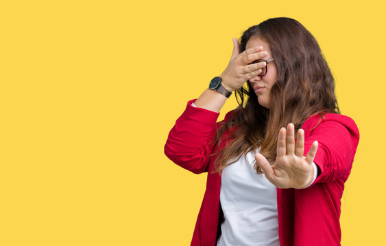 Beautiful plus size young business woman wearing elegant jacket and glasses over isolated background covering eyes with hands and doing stop gesture with sad and fear expression. Embarrassed