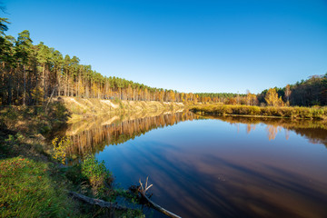 blue sky and clouds reflecting in calm water of river Gauja in latvia in autumn