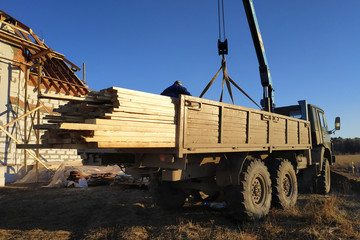 Fototapeta premium Unloading boards from the side of the crane with the help of people