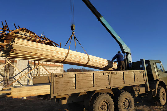 From the side of the cargo crane unload the boards for the construction of the house