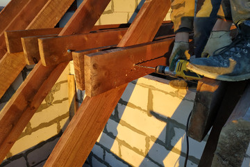 The worker uses a drill in the construction of the roof