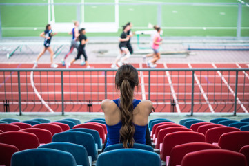 Fitness sport woman in fashion sportswear, sits looking at running sports girls, fitness exercise in the city street.