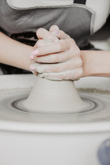 Creating a jar or vase of white clay close-up. Woman hands making clay jug.