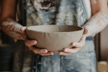 Pottery, clay, ceramics art concept - closeup on hands of young master with the large plate from...