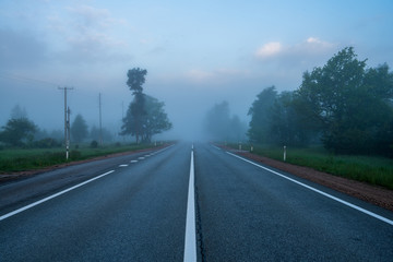 Naklejka premium empty asphalt road with white lines painted in misty morning