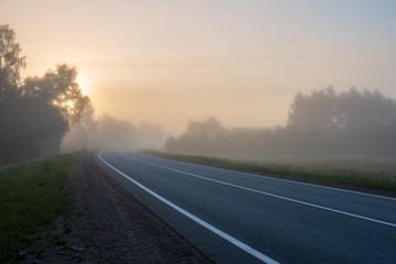 empty asphalt road with white lines painted in misty morning
