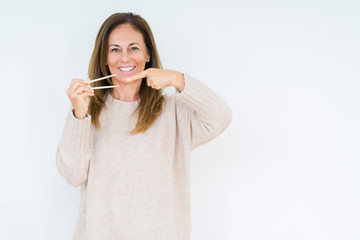 Middle age woman holding asian chopsticks over isolated background very happy pointing with hand and finger