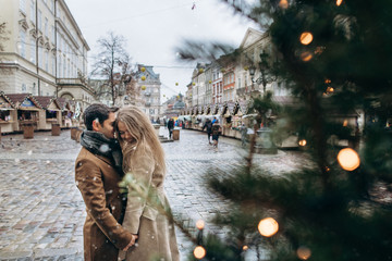 Fototapeta na wymiar Beautiful romantic lovely couple laughing and have fun on the central square of the Christmas Europe city