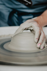 Creating a jar or vase of white clay close-up. Woman hands making clay jug.