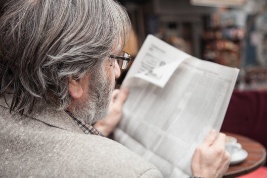 Senior man reading newspaper in outdoors