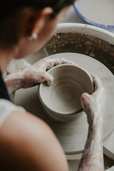 Creating a jar or vase of white clay close-up. Woman hands making clay jug.