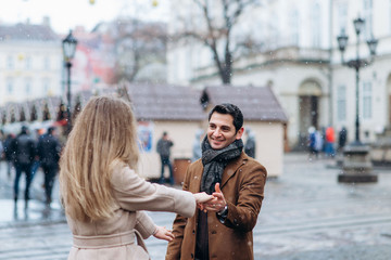 Handsome middle east man hold hands with his girlfriend on the central square of the Europe city