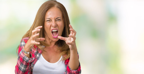 Beautiful middle age woman wearing over isolated background Shouting frustrated with rage, hands trying to strangle, yelling mad