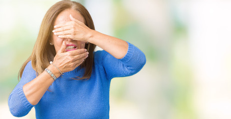 Fototapeta premium Middle age beautiful woman wearing winter sweater over isolated background Covering eyes and mouth with hands, surprised and shocked. Hiding emotion