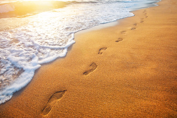 Fototapeta na wymiar beach, wave and footprints at sunset time