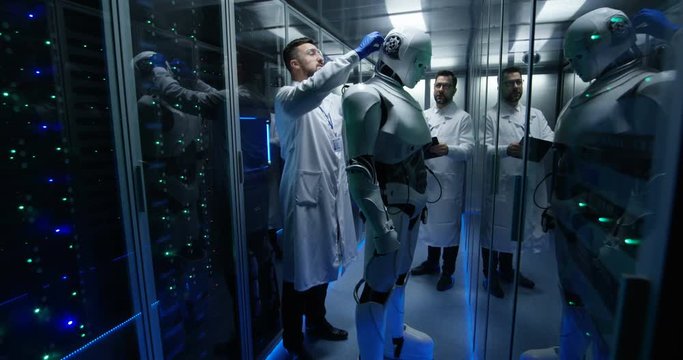 Two engineers in white gown test the robot in the data center by controlling the movements of the hands on the tablet via the user interface.