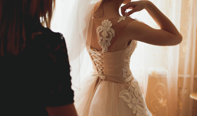 Bridal morning details. Beautiful girl is wearing her elegant white lace and satin dress. Happy wedding day picture.