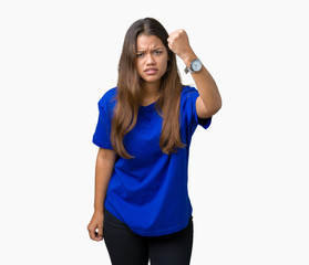 Obraz na płótnie Canvas Young beautiful brunette woman wearing blue t-shirt over isolated background angry and mad raising fist frustrated and furious while shouting with anger. Rage and aggressive concept.