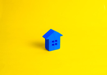 Fototapeta na wymiar A small wooden house stands on a yellow background. The concept of buying and selling real estate, renting. Search for a house. Affordable housing, credit and loans. Investments in business