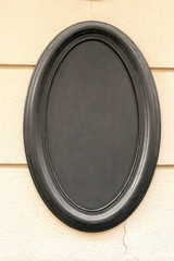 Oval empty blank black signboard on wall
